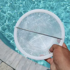 technician's hand holding a skimmer basket after cleaning a swimming pool