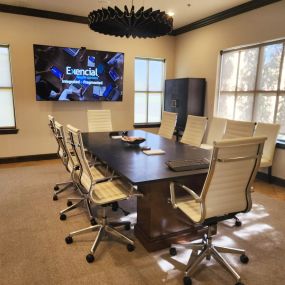 Conference room at Exencial Wealth Advisors with a central table, white chairs, and an illuminated presentation screen.