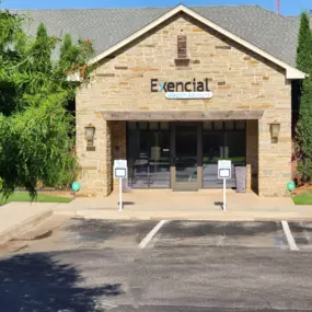 Exencial Wealth Advisors' Oklahoma City office with stone walls, company signage, and surrounding greenery.