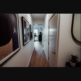 Hallway with plank flooring and modern abstract art on the walls leading to the bedroom area