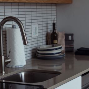 Elevated kitchen counter area with gooseneck  faucet and backsplash tiling