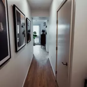 Hallway with plank flooring and modern abstract art on the walls leading to the bedroom area