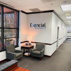 The lobby of the Exencial Wealth Advisors Huntersville, North Carolina office features a welcoming atmosphere with comfortable seating and a prominently displayed company logo.
