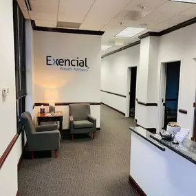 The lobby of the Exencial Wealth Advisors Huntersville, North Carolina office features a welcoming atmosphere with comfortable seating and a prominently displayed company logo.