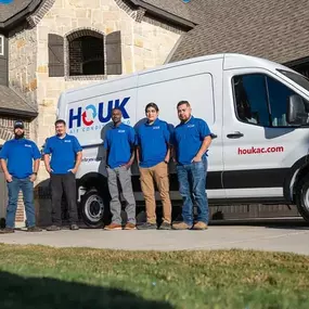 Houk Air Conditioning service technicians standing in front of a service van