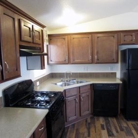 an empty kitchen with wooden cabinets and black appliances