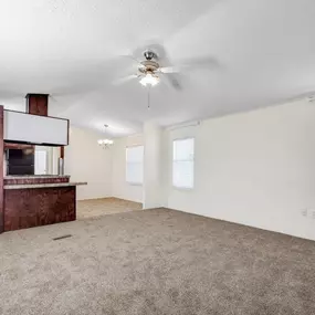 an empty living room with a ceiling fan and a bookshelf