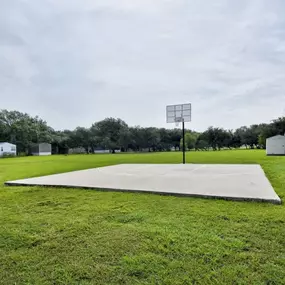 a basketball court sits in the middle of a grassy field