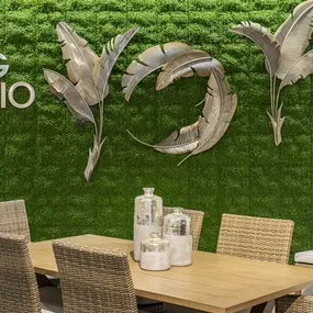 Elegant dining setup with natural wicker chairs and a green moss wall backdrop.