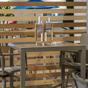 Modern patio furniture with wooden accents, featuring a compact high-top table and matching chairs.