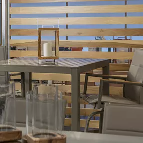 Stylish patio set with a wood-accented table and matching chairs in a modern showroom.