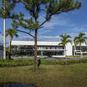 Exterior of a Rooms To Go Patio store surrounded by palm trees.