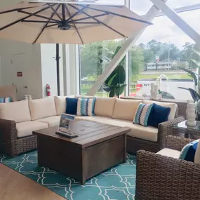 Cozy wicker outdoor sectional with beige cushions, a wooden fire pit table, and a large patio umbrella.