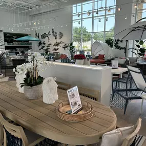 Elegant oval wood patio dining table with stylish seating and coastal-inspired décor.