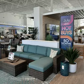 Inviting wicker patio sectional with teal cushions and a seasonal promotional display.