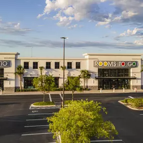 Front view of Rooms To Go Kids & Patio store with palm trees and modern design.