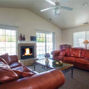 View of resident sitting room with two brown leather look couches facing one another with a stone-framed fireplace on the wall between