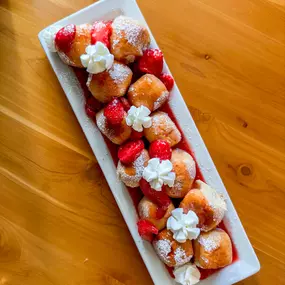 Cinnamon Sugar Balls Topped with Strawberry Glaze, Whipped Cream, and powdered Sugar.