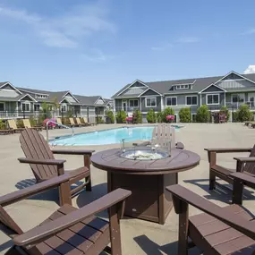 a patio with a table and chairs next to a pool with houses in the background