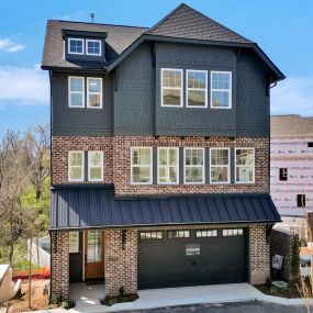 a beautiful newly constructed home with black siding and brick