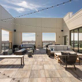 Rooftop terrace with couches tables and chairs and a pool in the background