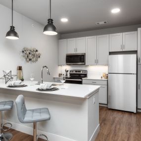 a kitchen with white cabinets and a white island with two chairs