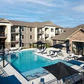 a swimming pool with chairs and umbrellas in front of a building