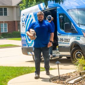 A team of plumbers from Covenant Plumbing arrives at a residential home in Bloomington-Normal, IL, in their marked service van. The team, wearing uniforms with the Covenant Plumbing logo, is ready to provide professional plumbing services to the homeowner