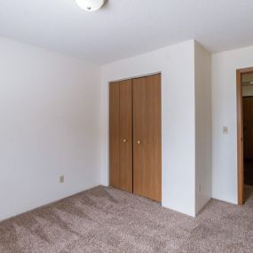 a bedroom with white walls and a door to a hallway