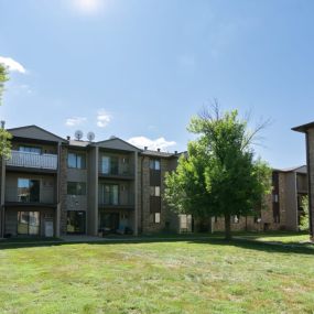 An exterior view of a brick apartment building with green grass