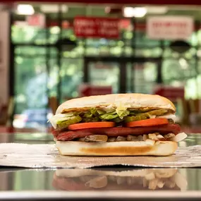 A Five Guys hot dog sits on the counter in a Five Guys restaurant.