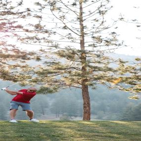 a man swinging a golf club in the woods