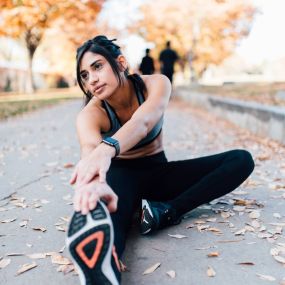 a woman sitting on the road holding a pair of running shoes