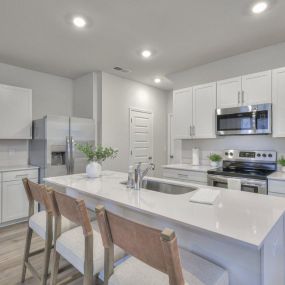 Spacious kitchen with quartz countertops including kitchen island and stainless steel appliances.