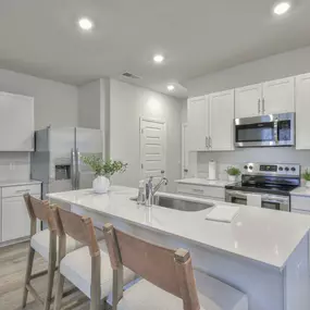 Spacious kitchen with quartz countertops including kitchen island and stainless steel appliances.