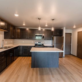 A kitchen with dark wood cabinets and a white counter top.