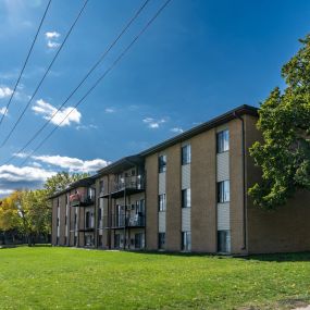 a large brick apartment building with a green grass