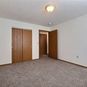 an empty living room with carpet and two doors to a closet