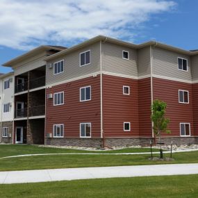 an exterior view of an apartment building with grass and a sidewalk