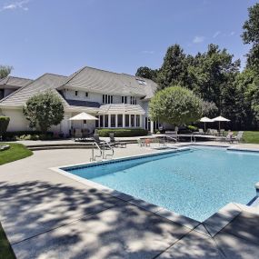 Pool with basketball hoop in a large backyard.