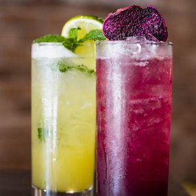 Fresh Green and Purple colored drinks with fresh garnish.