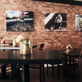 Dining room of Holden Oversoul Kitchen & Oysterbar. Brick wall with photos from the farm. Tables adorned with fresh flowers.