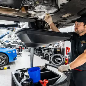 A service technician working under a vehicle on a lift