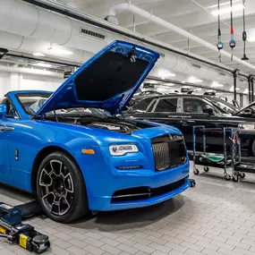 A Rolls-Royce in a service bay with the hood up