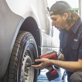 A service technician screwing lug nuts on a vehicle