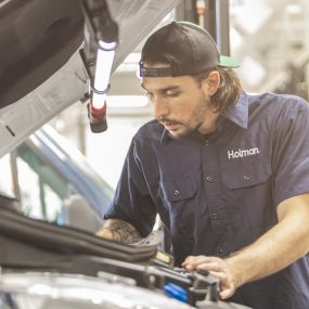 A service technician working under the hood of a vehicle