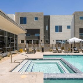 a swimming pool with chairs and a building in the background