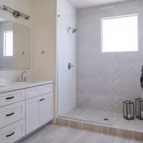 a white bathroom with a shower and a sink and a mirror