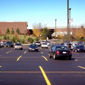 Cars parked in a parking lot that has fresh asphalt pavement and yellow line striping.