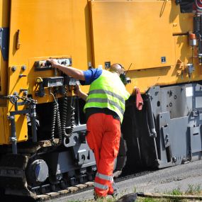 Smooth Paving employee in PPE working with a large pavement machine.